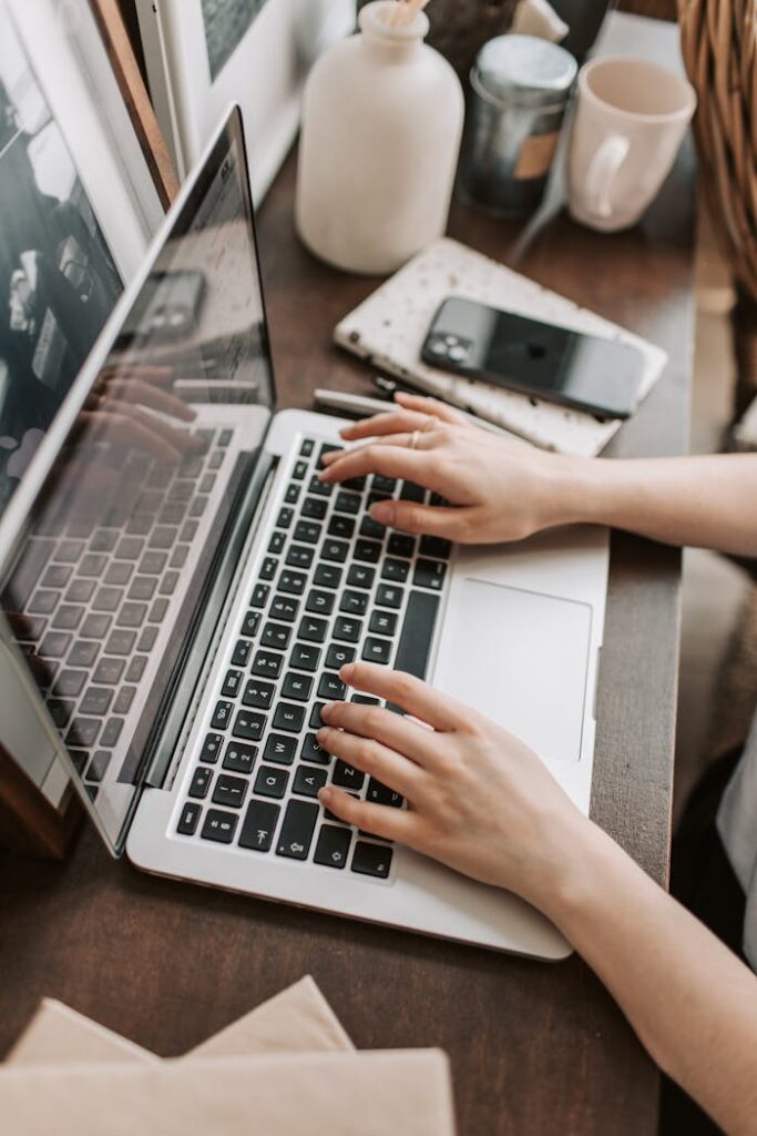 pexels-photo-4050312 From above of unrecognizable woman sitting at table and typing on keyboard of computer during remote work in modern workspace